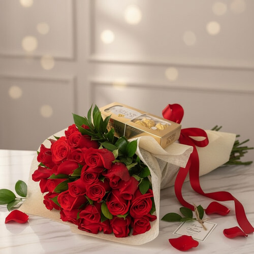 Ramo de rosas rojas envuelto en papel crema con lazo rojo y caja de bombones dorada sobre mesa de mármol blanco
