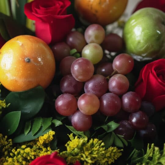 Primer plano extremo del Arreglo Floral Batista, mostrando rosas rojas, uvas, maracuyá y manzana verde con gotas de rocío, te
