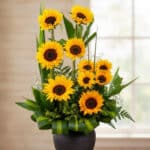 Arreglo floral GIULIANA con girasoles radiantes en un jarrón oscuro, ideal para ecommerce de floristería, con fondo elegante