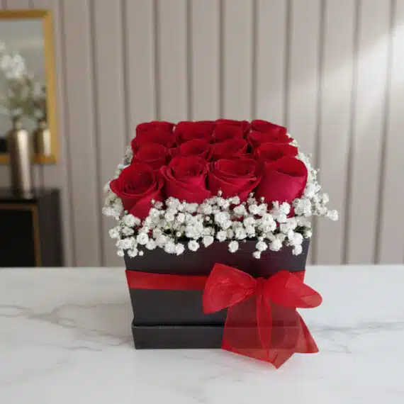 Arreglo Floral Pétalos: Rosas Rojas Frescas en Caja Elegante Arreglo floral Pétalos con rosas rojas frescas y gypsophila en una caja negra con lazo rojo, sobre mármol blanco en un entorn