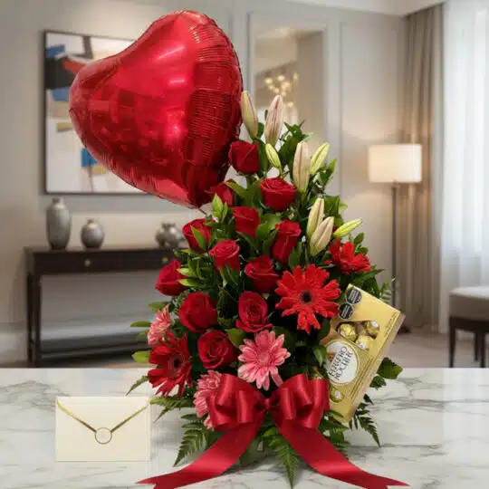 Arreglo floral "Te Amo" con rosas rojas, liliums blancos, gerberas rosadas y rojas, follaje verde, globo de corazón rojo, cho