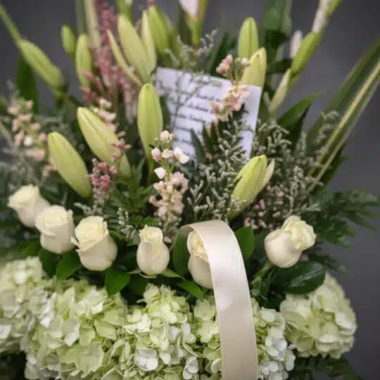 Fotografía macro premium de arreglo fúnebre 'Eterno Descanso' con lirios, rosas blancas y hortensias verdes, rocío sutil, cin