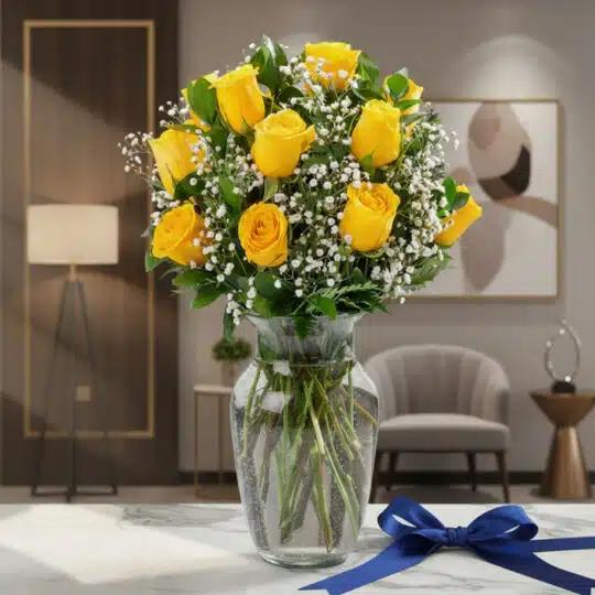 Jarrón de cristal con doce rosas amarillas frescas y gypsophila, sobre una mesa de mármol con un lazo azul marino, en un ambi