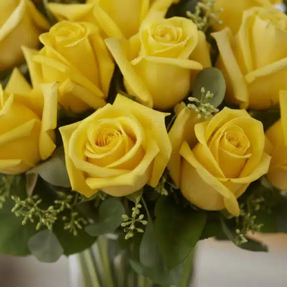 Primer plano extremo de un arreglo floral Jarron Floral PANDORA con 36 rosas amarillas, mostrando textura hiperrealista, gota