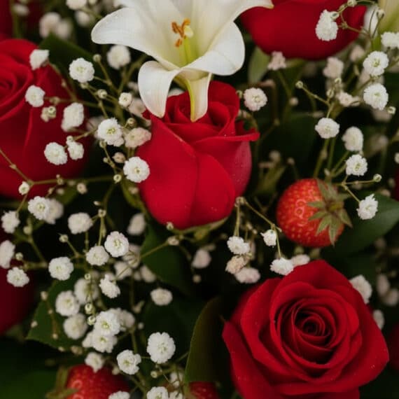 Primer plano extremo de un arreglo floral 'Jarrón Todo Para Ti' con rosas rojas vibrantes, lirios blancos y pequeñas flores b