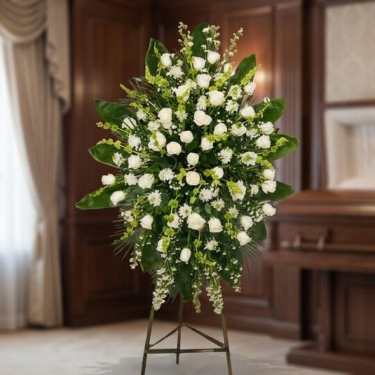 Pedestal fúnebre 'Nunca te Olvidaré' con rosas blancas, lirios y follaje verde, presentado en una sala de velación premium co