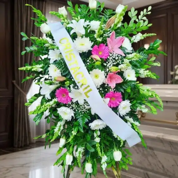 Pedestal fúnebre Sagrado con flores blancas, lirios, crisantemos y toques de gerberas rosas, en una sala de velación premium