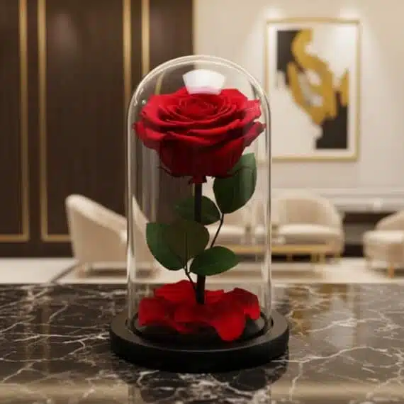 Rosa Preservada Roja en Cúpula de Cristal: Regalo Eterno y Elegante Rosa preservada roja en cúpula de cristal sobre una mesa de mármol negro, con un fondo elegante de lobby de hotel boutique.