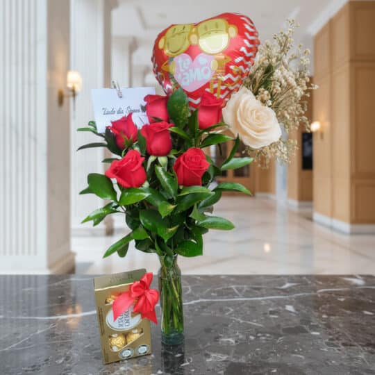 Arreglo floral Solitario con Rosas Me Enamoras, rosas rojas y una rosa blanca, follaje verde, globo de corazón 'Te Amo' y caj